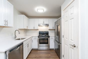 a white kitchen with stainless steel appliances and white cabinets